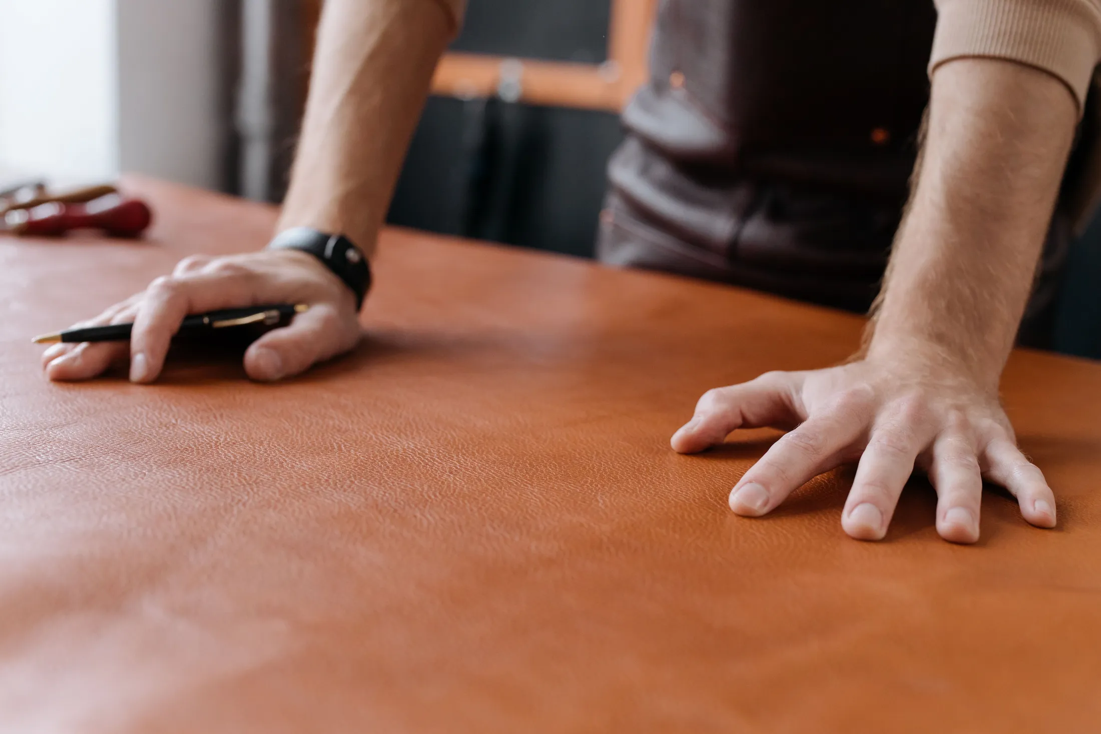 A leatherworker's hands on a piece of full-grain leather